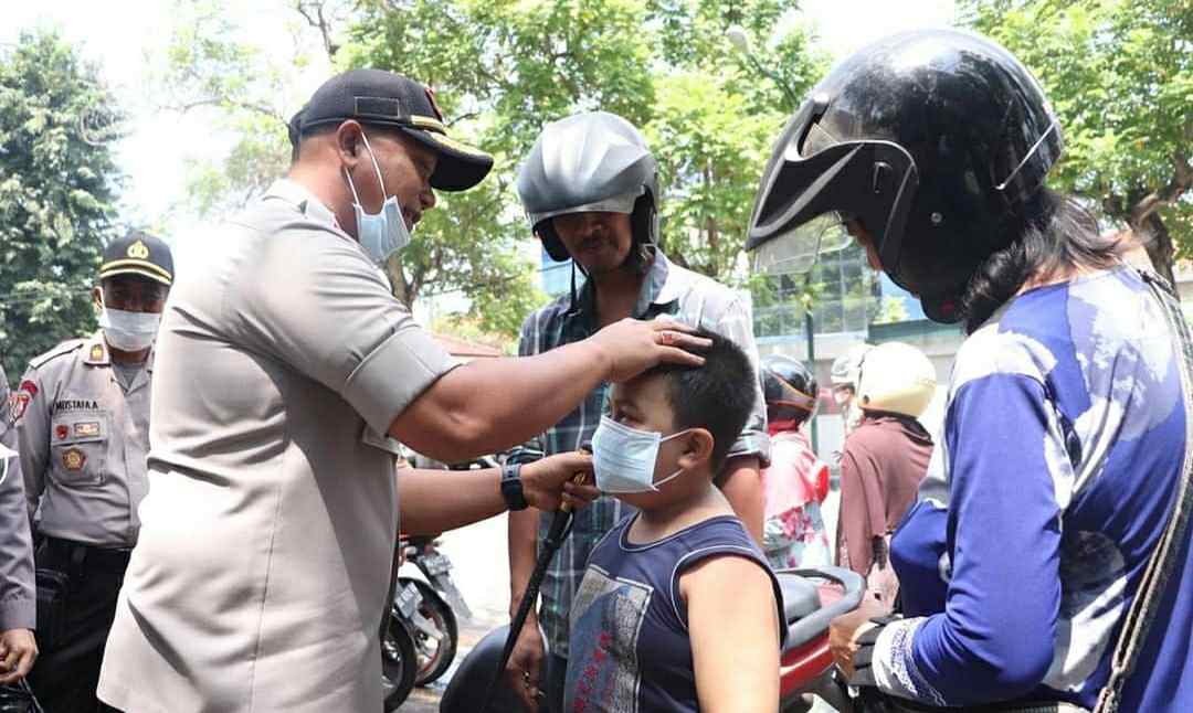 Anggota Polisi saat pasangkan masker ke anak-anak