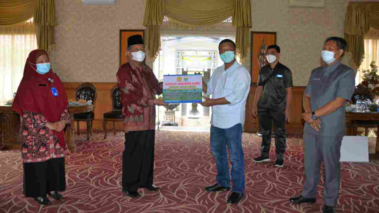 Abdullah Sani saat serahkan bantuan yang diterima oleh Romi Hariyanto 